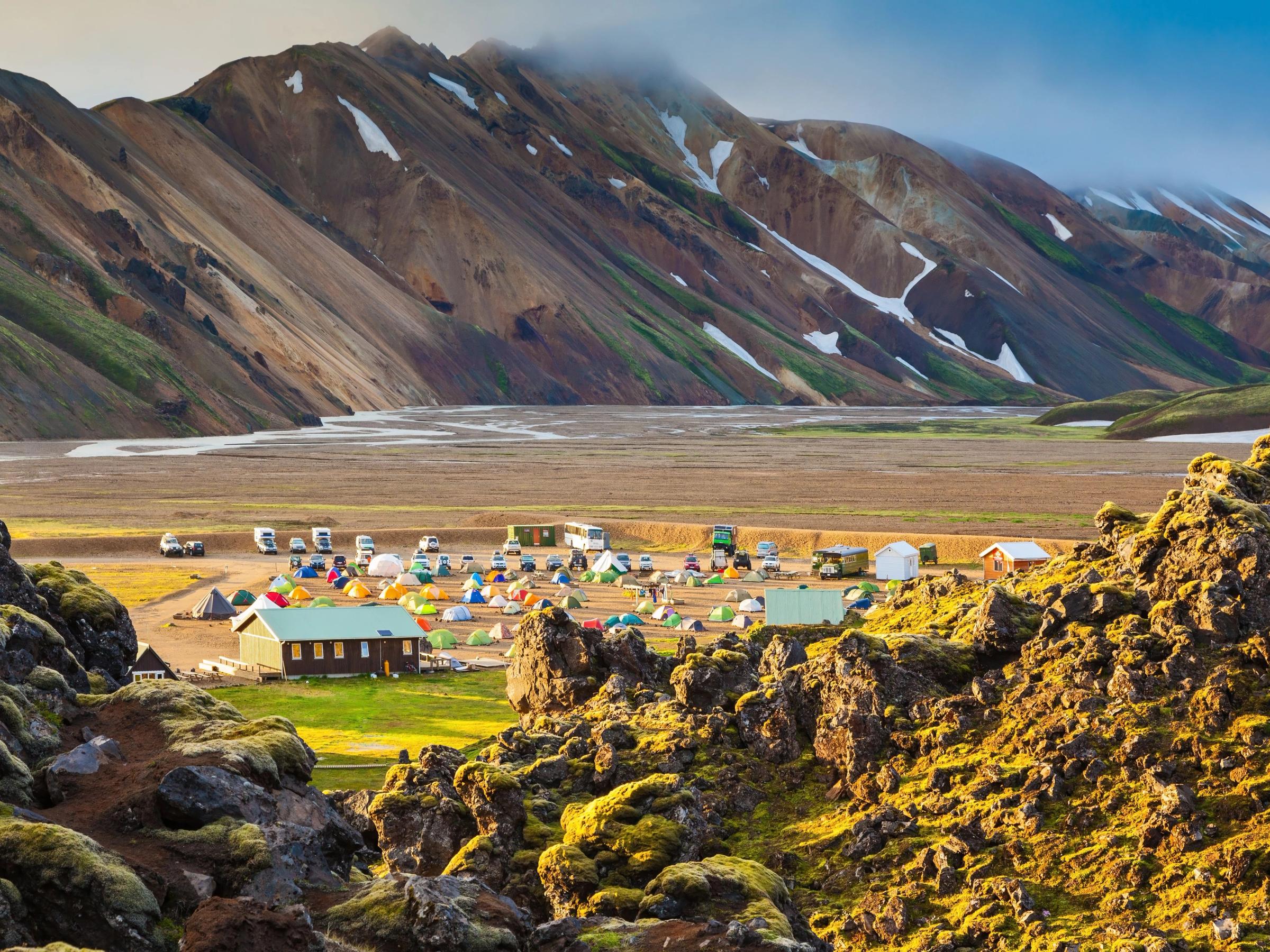 a group of tents are sitting in a field with mountains in the background .
