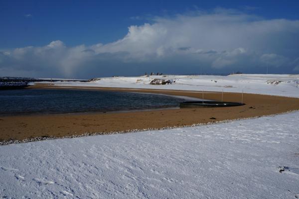 a snowy beach with a body of water in the background