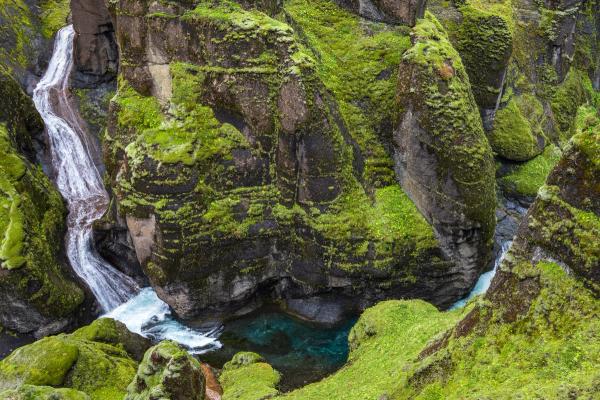 Moss-covered canyon with a waterfall and turquoise river.