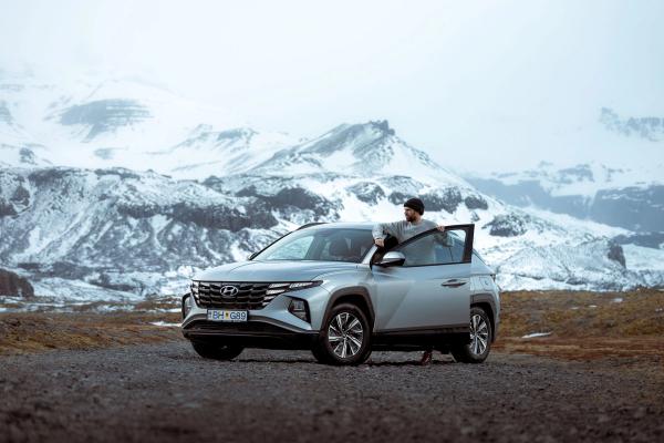 A person standing beside a Hyundai Tucson rental car in Iceland.