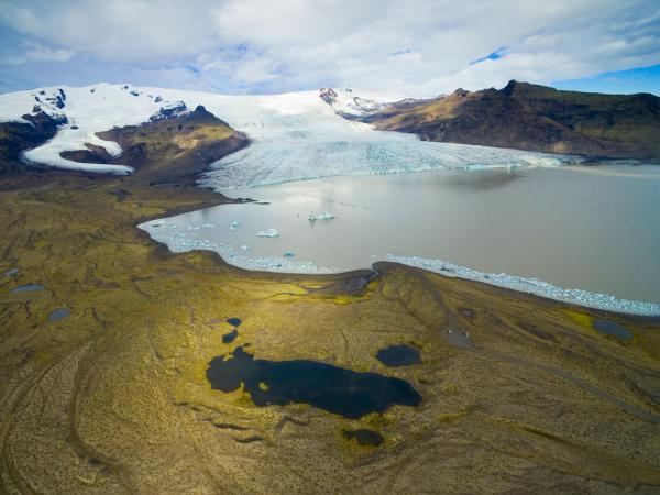 an aerial view of a glacier surrounded by mountains and a lake .