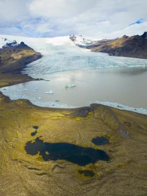 an aerial view of a glacier surrounded by mountains and a lake .