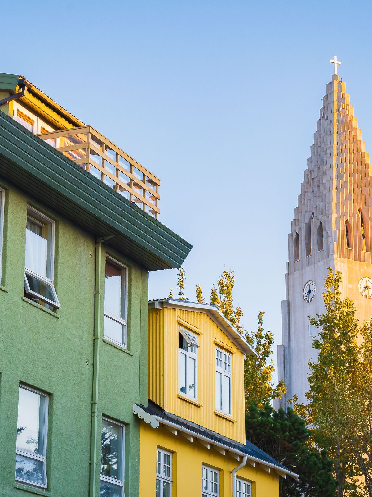 un edificio verde y amarillo con una torre de reloj al fondo.