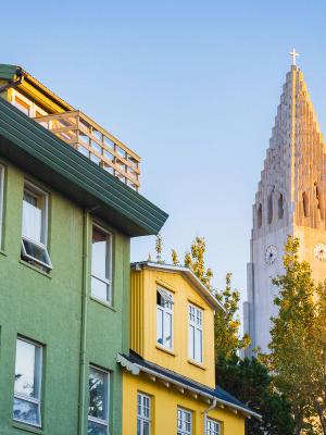 un edificio verde y amarillo con una torre de reloj al fondo.