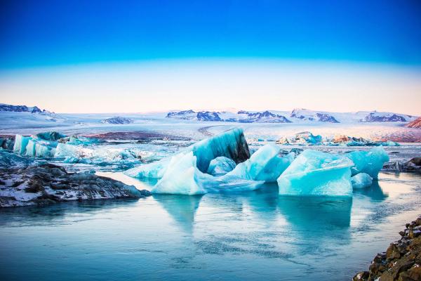 icebergs are floating in a lake with mountains in the background .