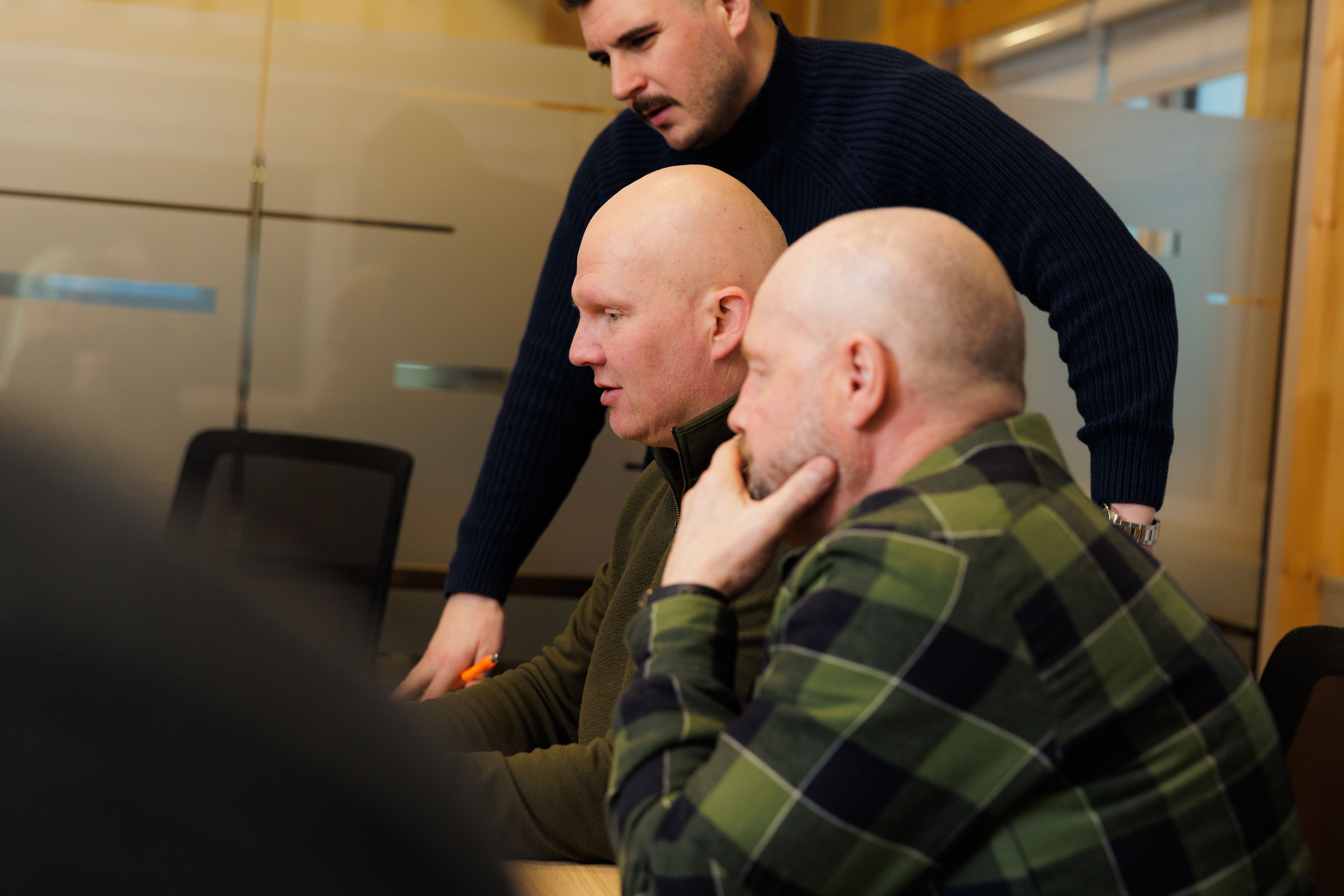 a group of men are looking at a computer screen together .
