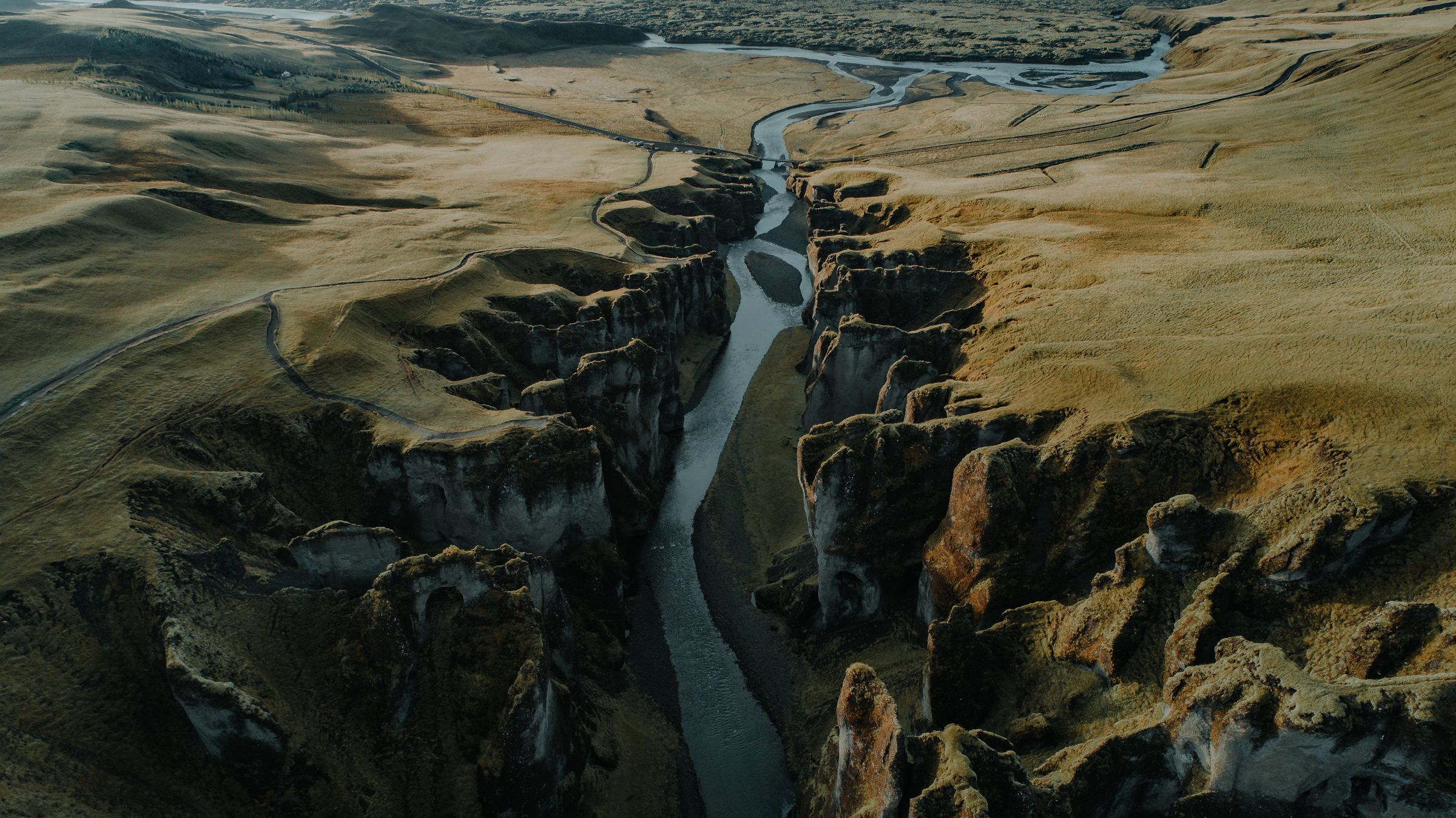 Aerial view of a river flowing through a deep, rocky canyon surrounded by vast, grassy plains.