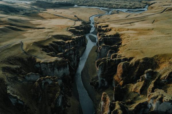 Aerial view of a river flowing through a deep, rocky canyon surrounded by vast, grassy plains.