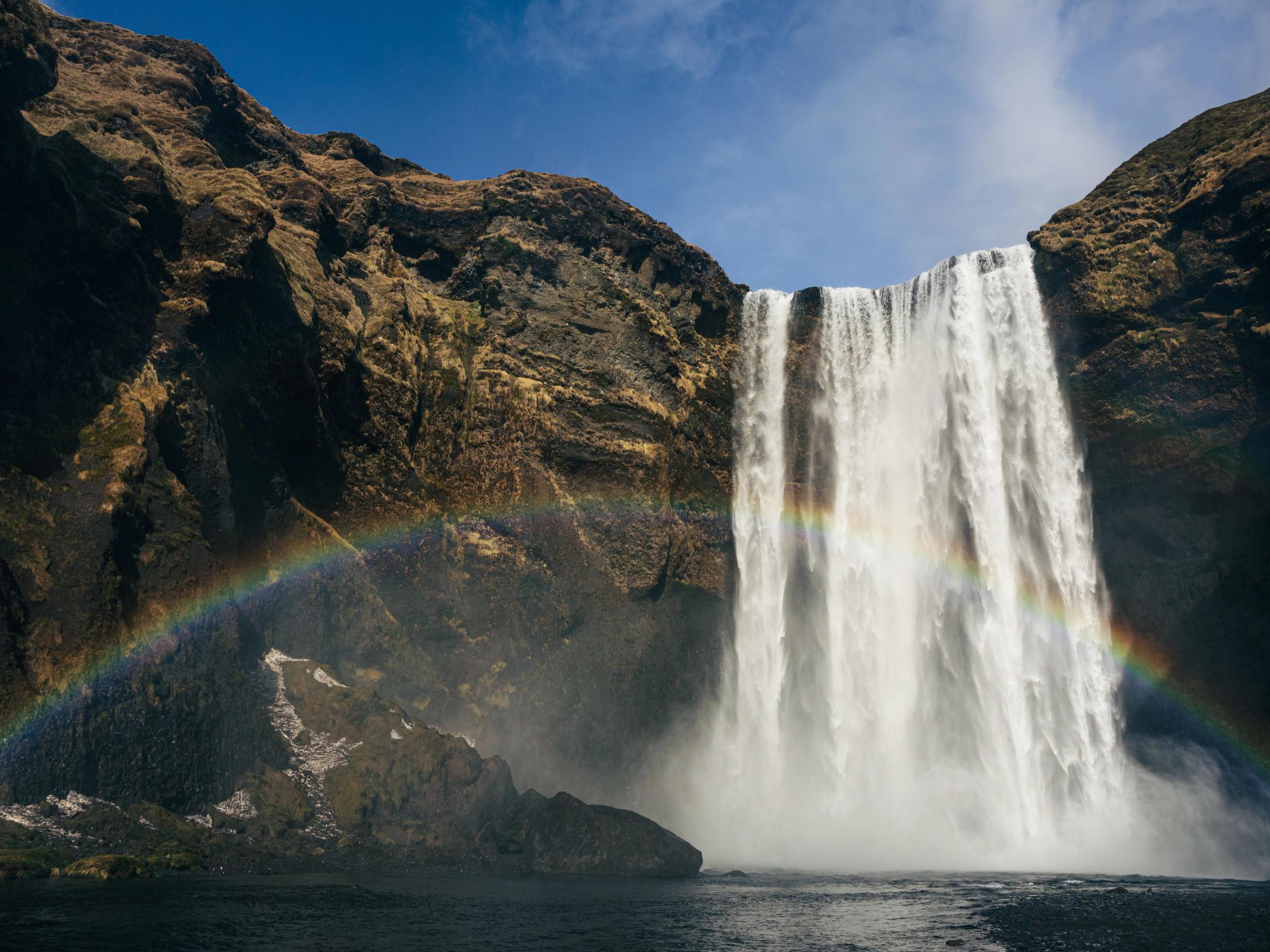 La cascada islandesa de Skogafoss en un día soleado con un arcoiris delante