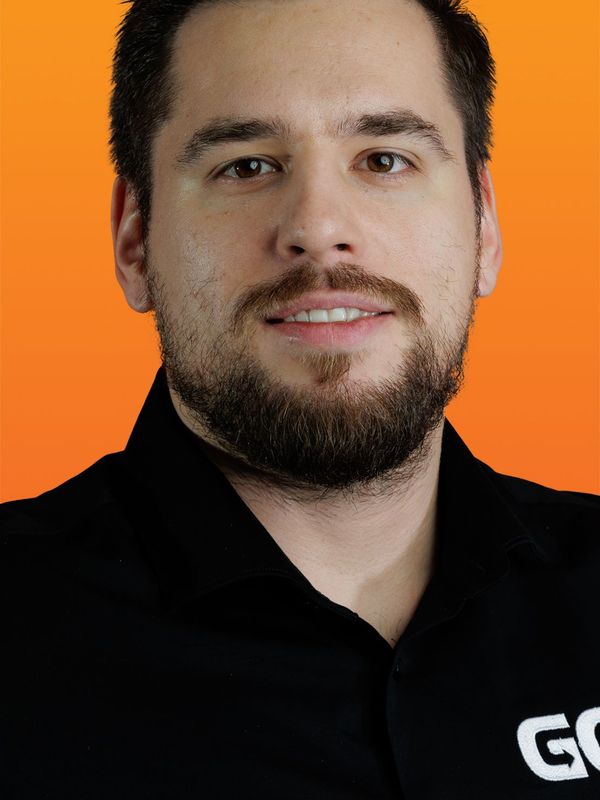 a man with a beard wears a black shirt with the letter g on it