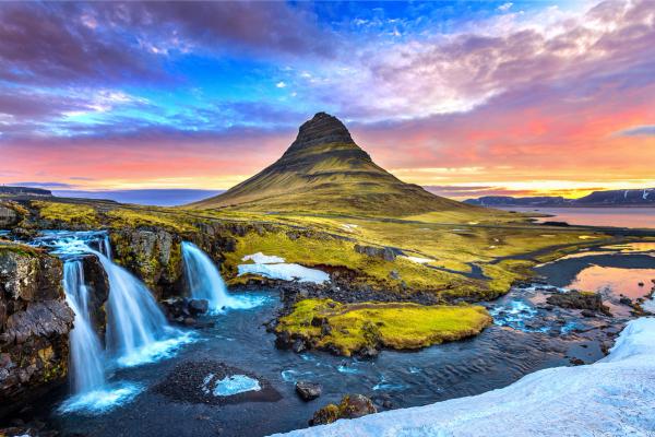 there is a waterfall in the foreground and a mountain in the background in iceland.