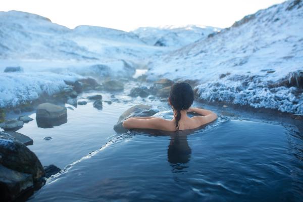 a woman is taking a bath in a hot spring in the mountains in iceland.
