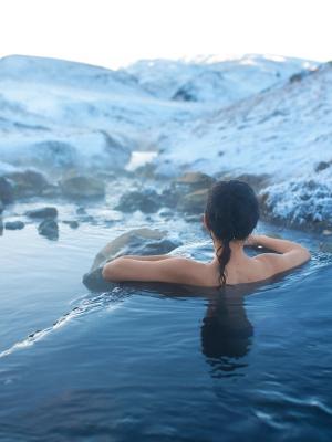 a woman is taking a bath in a hot spring in the mountains in iceland.