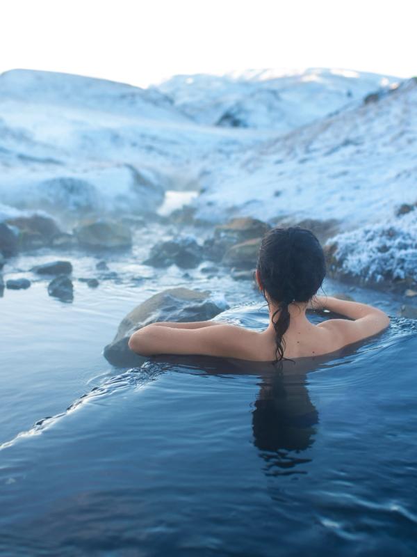 a woman is taking a bath in a hot spring in the mountains in iceland.