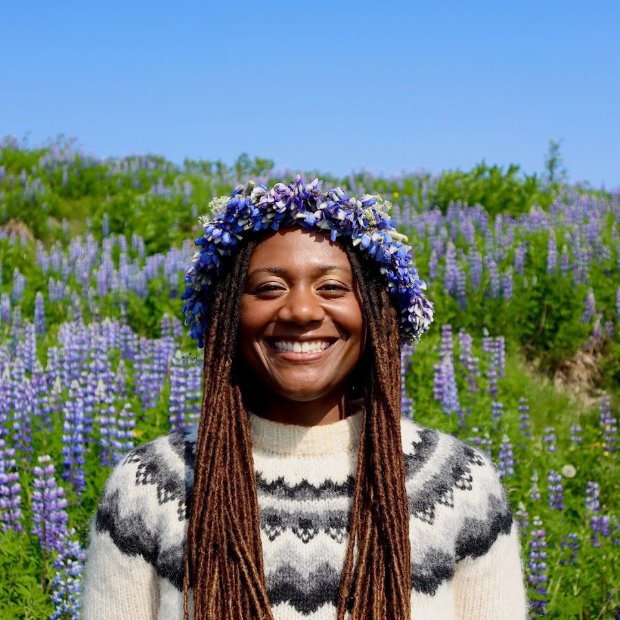 a woman wearing a flower crown is smiling in a field of purple flowers .
