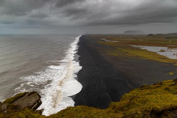 a view of the ocean from a cliff on a cloudy day .