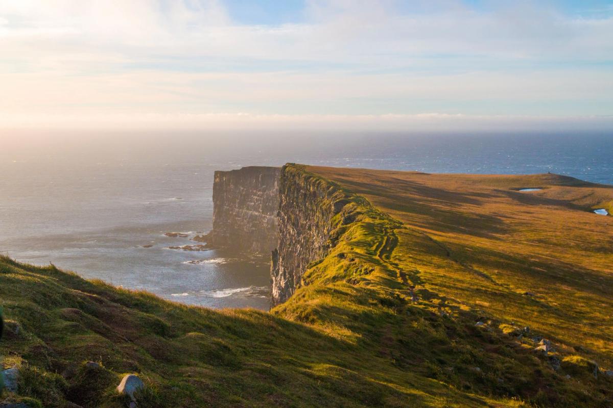 a view of a cliff overlooking the ocean at sunset .