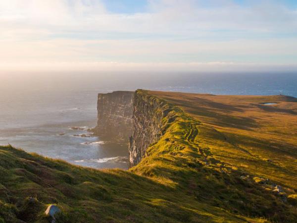 a view of a cliff overlooking the ocean at sunset .