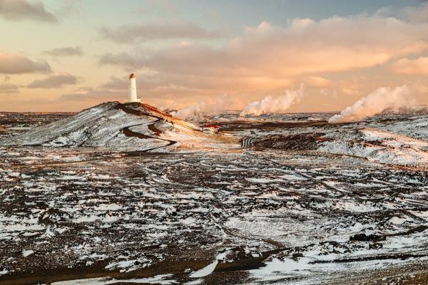 Paisaje nevado con un faro blanco en la cima de una colina