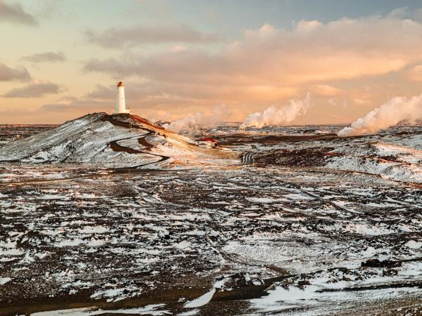 a lighthouse on top of a snow covered hill in the middle of a field .