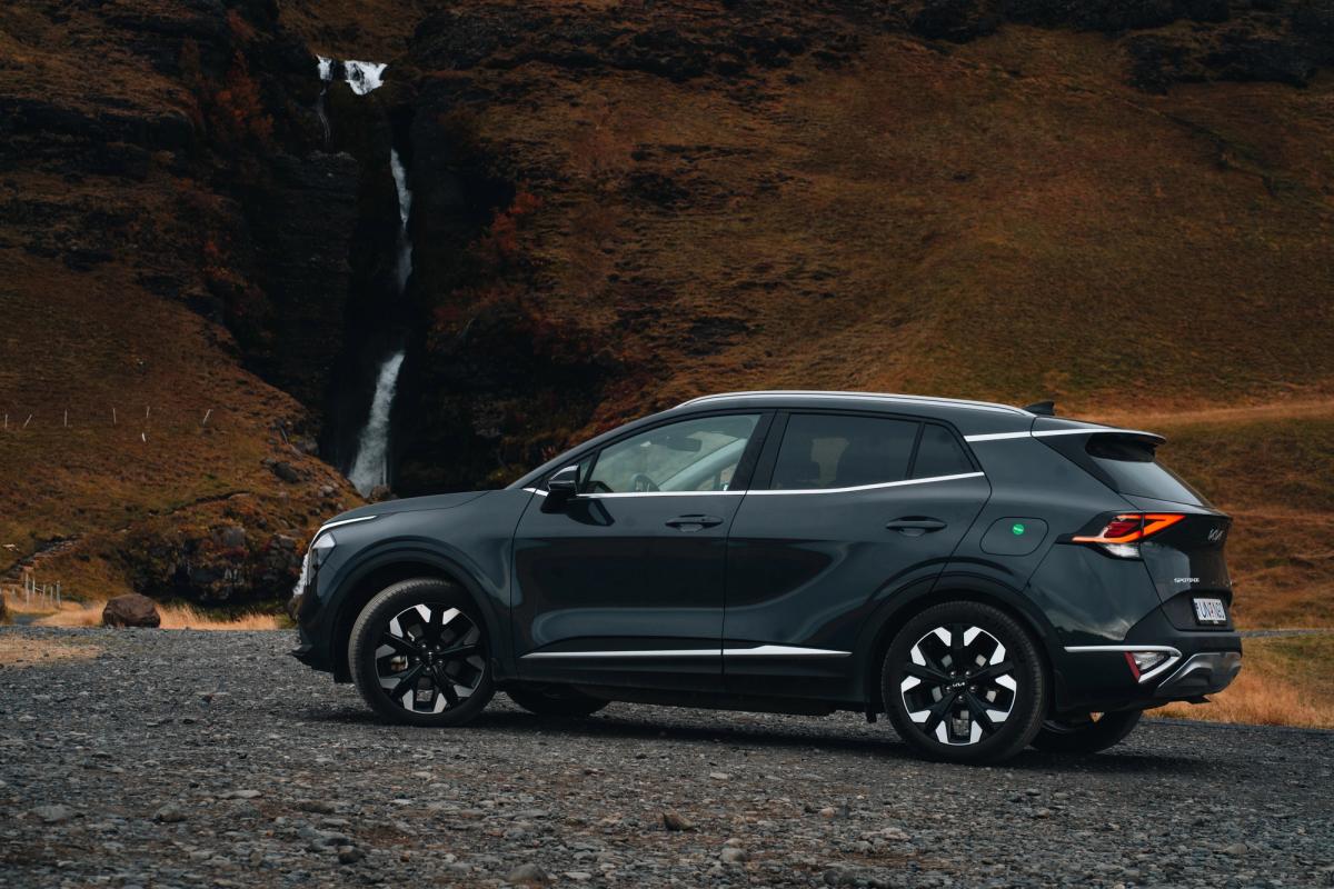 Kia Sportage-leigujeppi á Íslandi, lagt á malarvegi neðan við foss