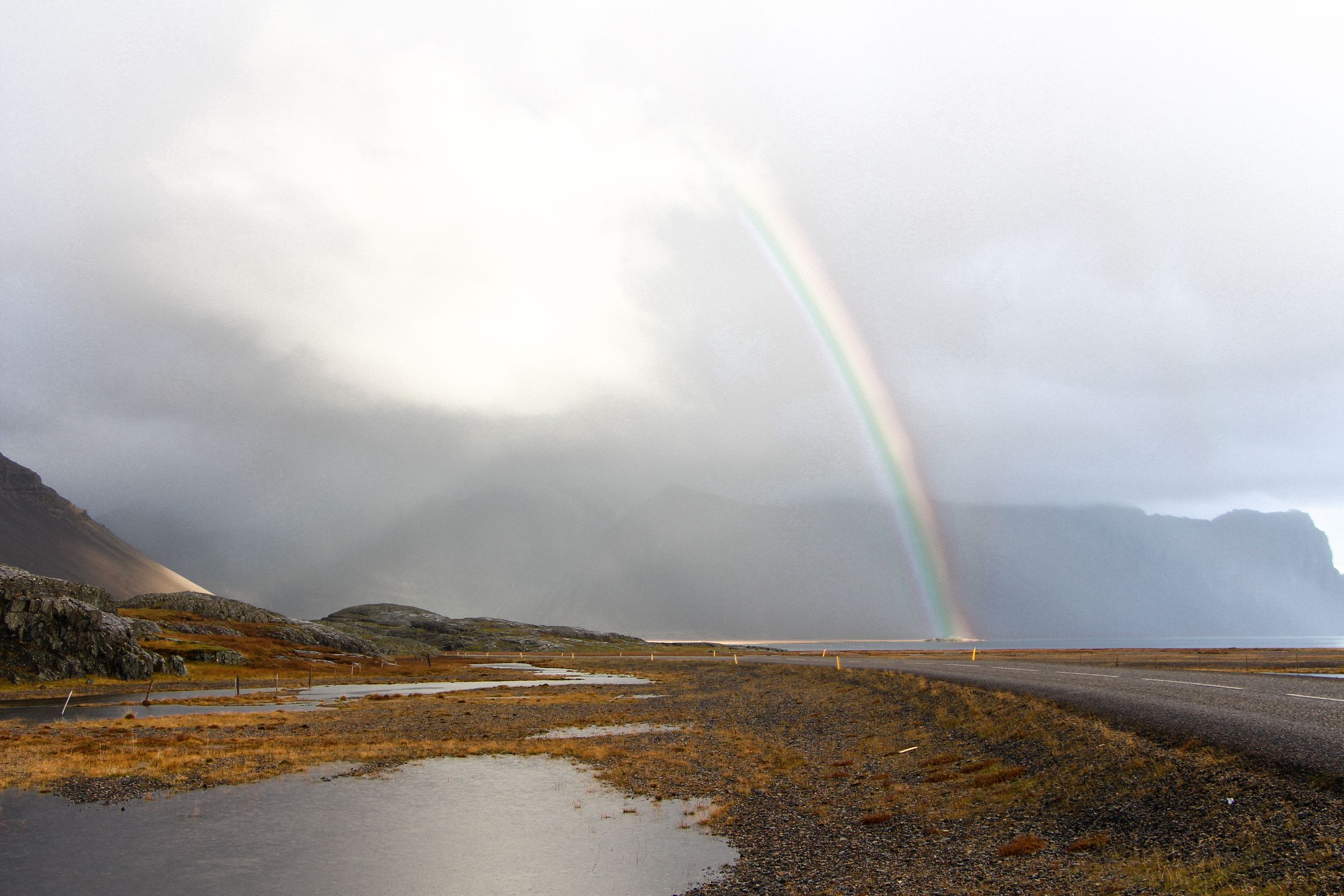 there is a rainbow in the sky over a body of water .