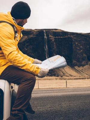 Man sitting on his 4x4 checking a map of Iceland