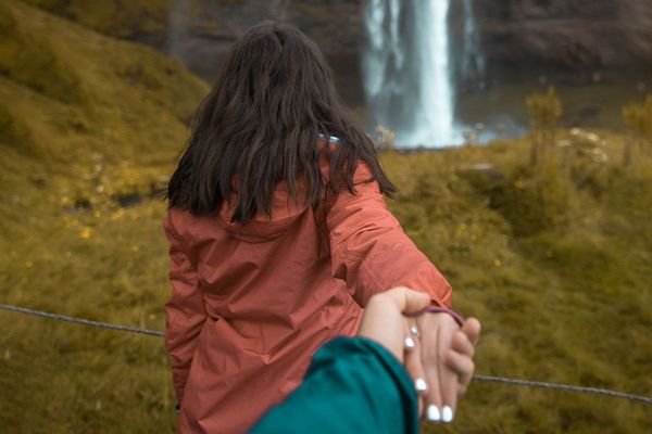 A woman walking to a beautiful waterfall in iceland