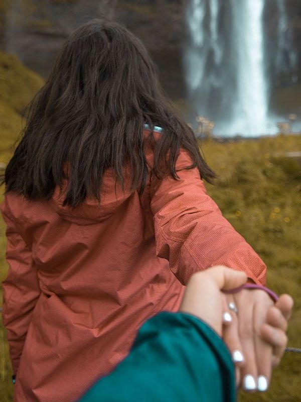 Best Places To Visit In Iceland A woman walking to a beautiful waterfall in iceland