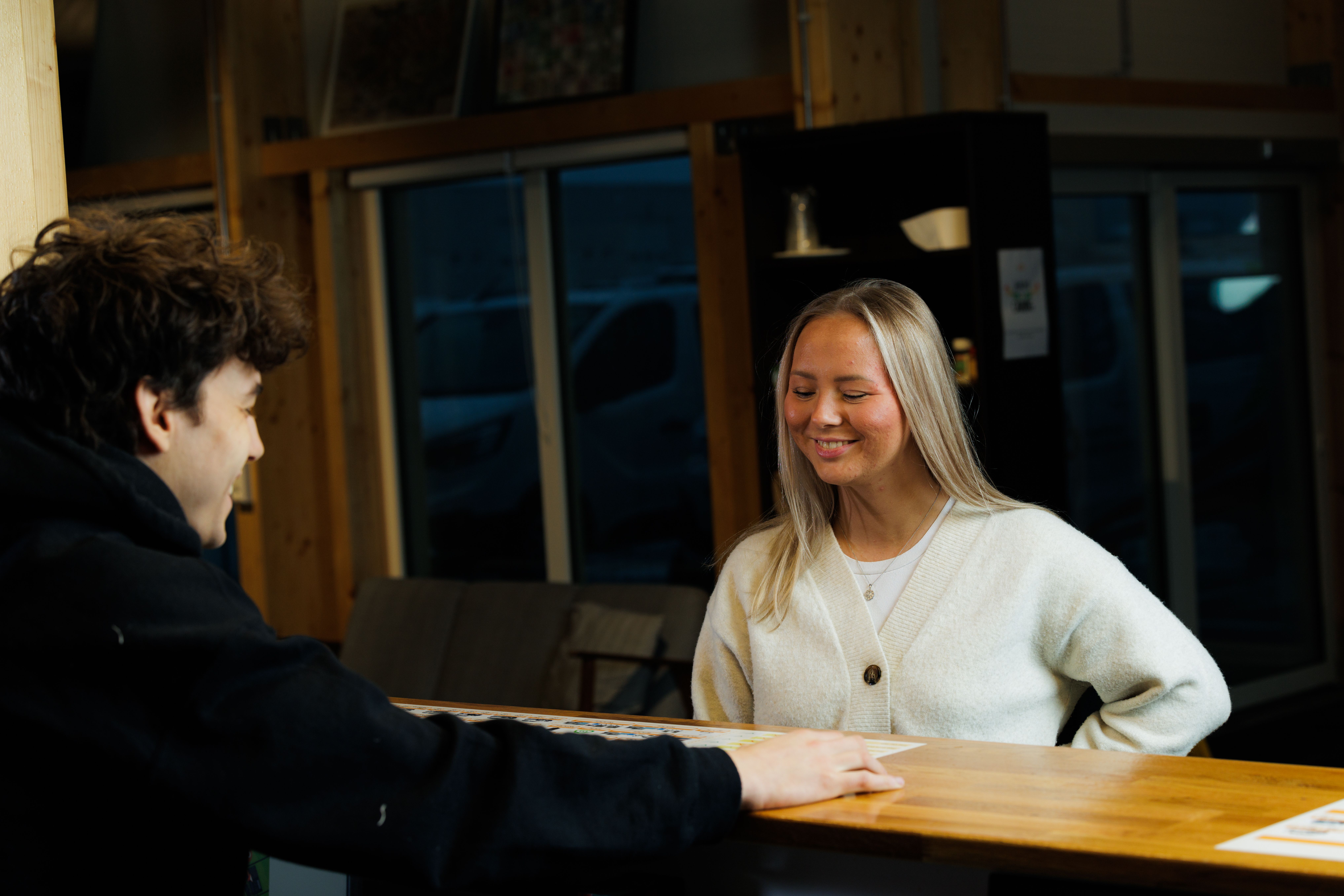 a man and a woman are talking at a counter in a restaurant .