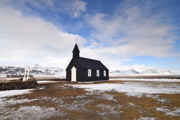 una iglesia de madera negra en medio de un campo nevado