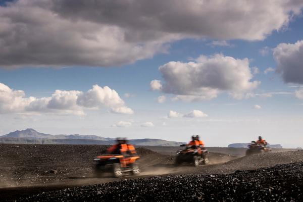 a group of people are riding atvs on a dirt road .