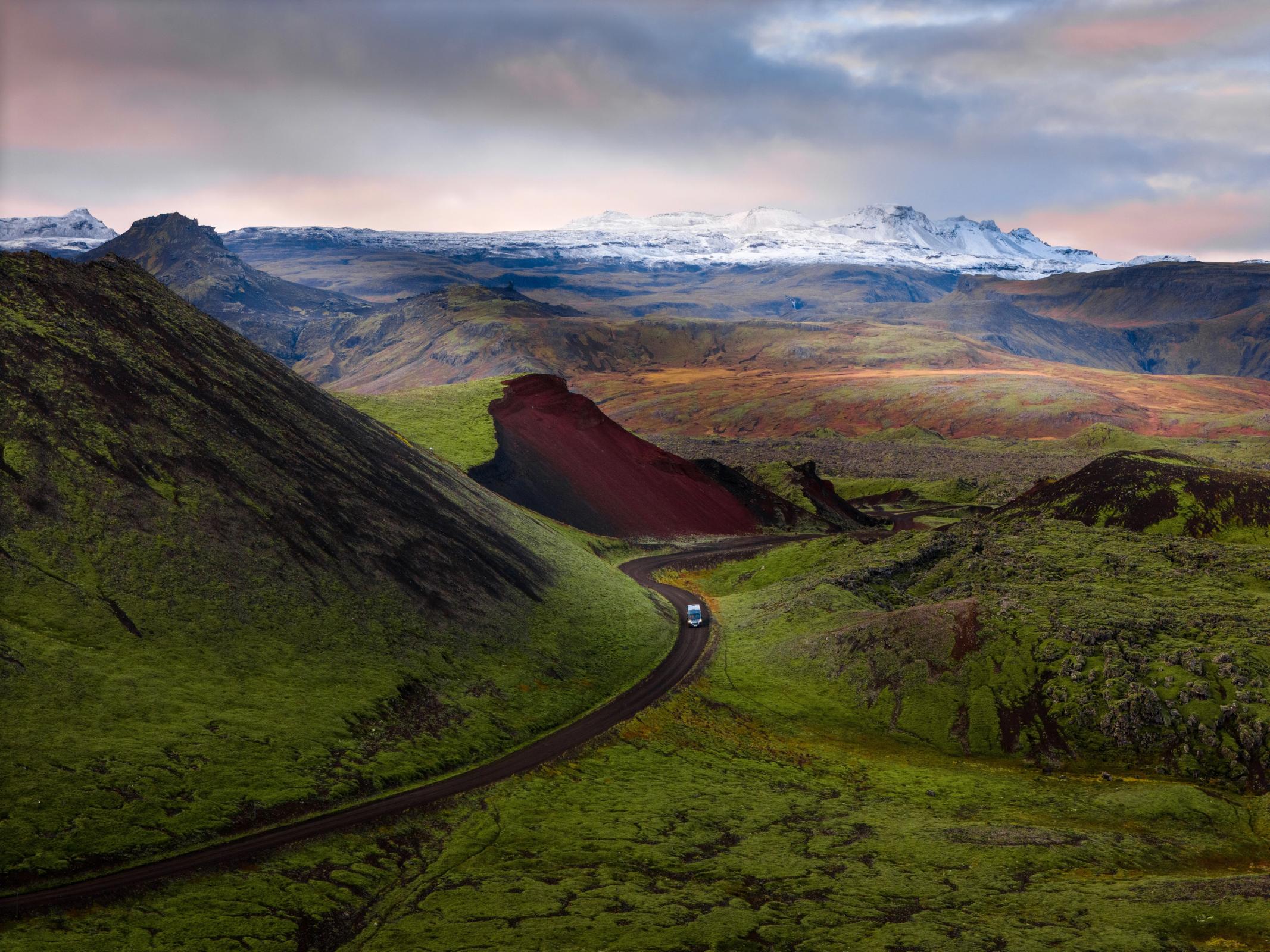 a car is driving down a road in the mountains .