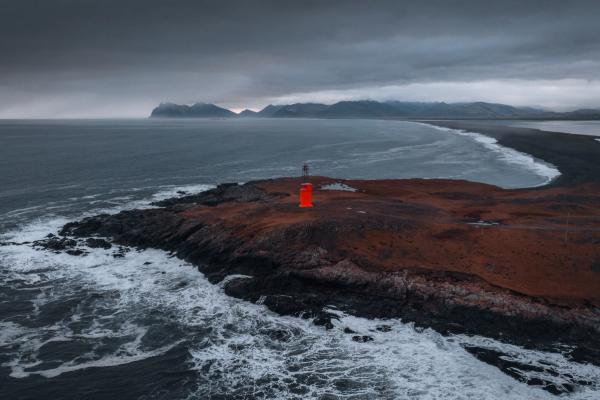 an aerial view of a lighthouse on a small island in the middle of the ocean .