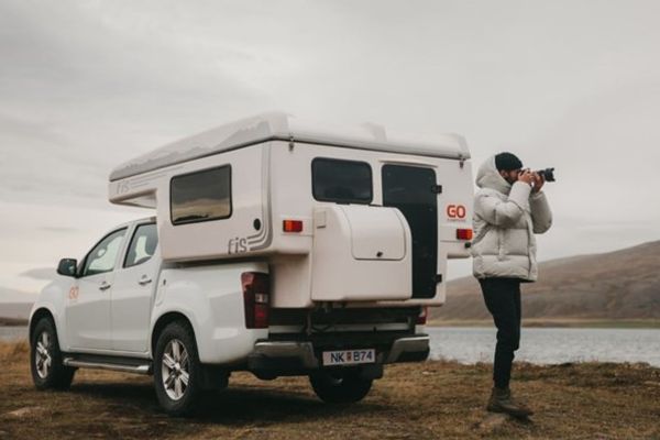 a man is taking a picture of a truck with a camper attached to it .