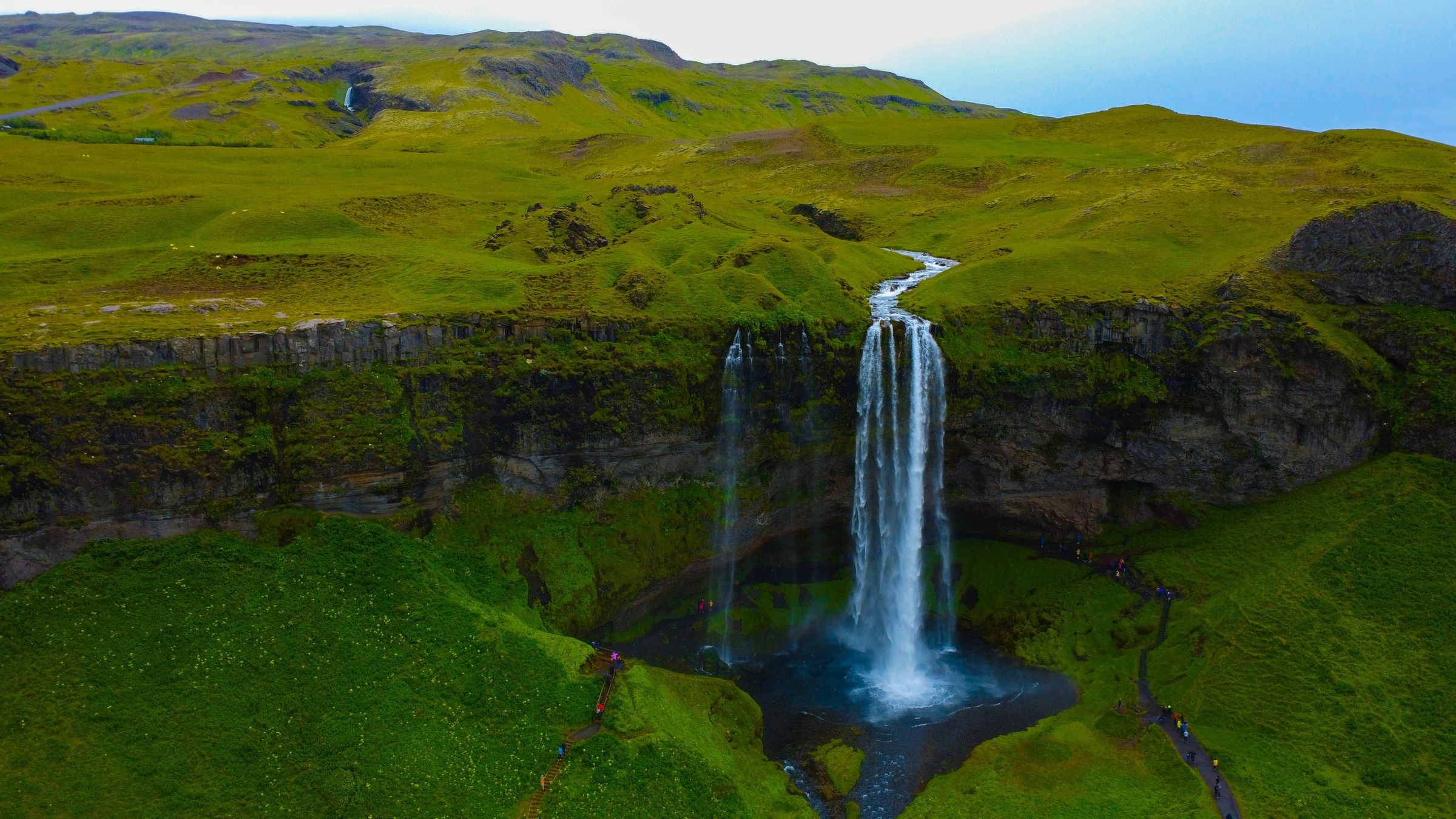 a waterfall with lush green moss around it on a clear day