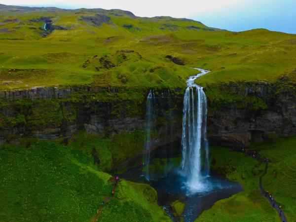 a waterfall with lush green moss around it on a clear day