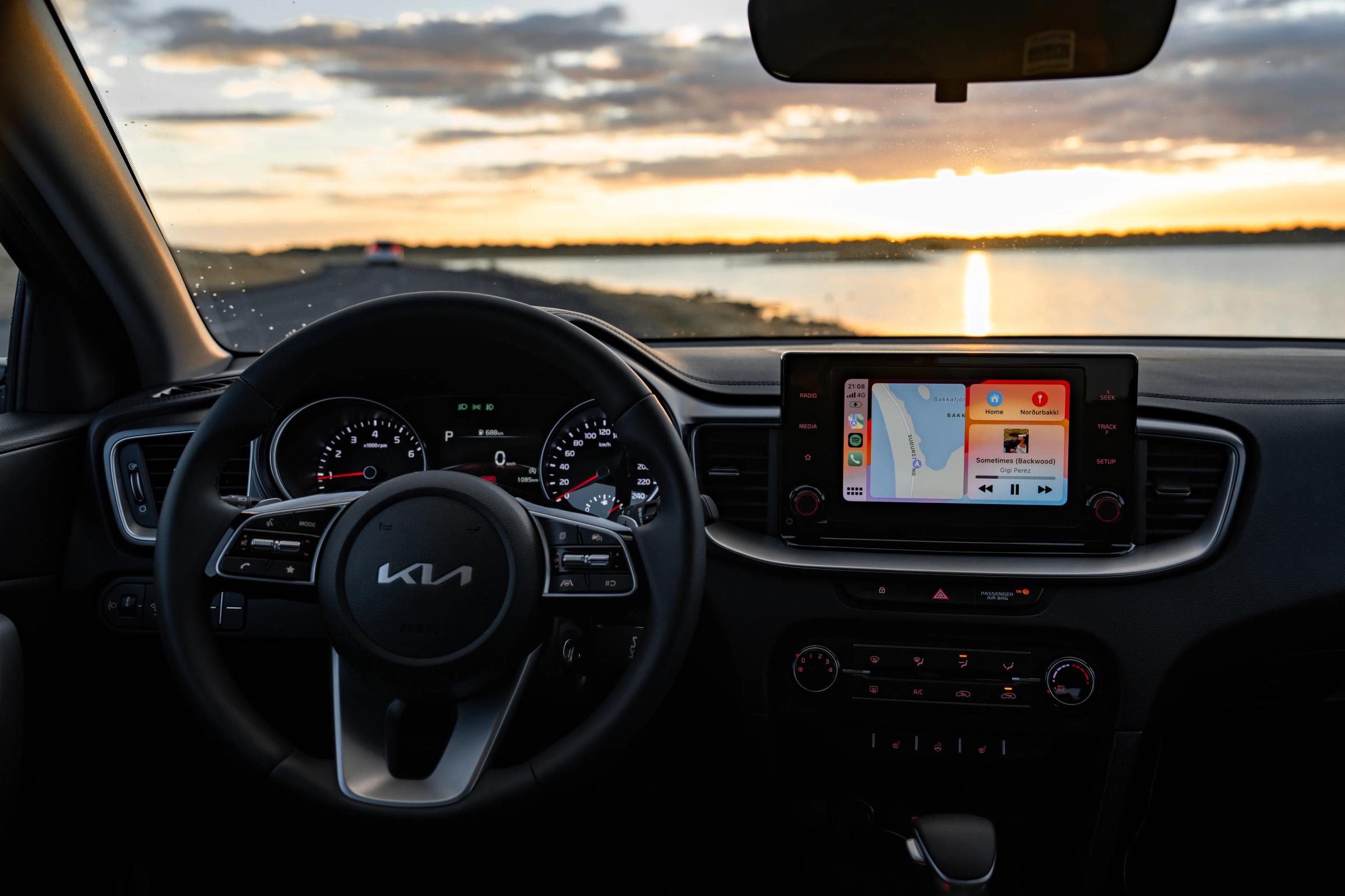 Kia Ceed interior view with steering wheel and touchscreen over coastal road