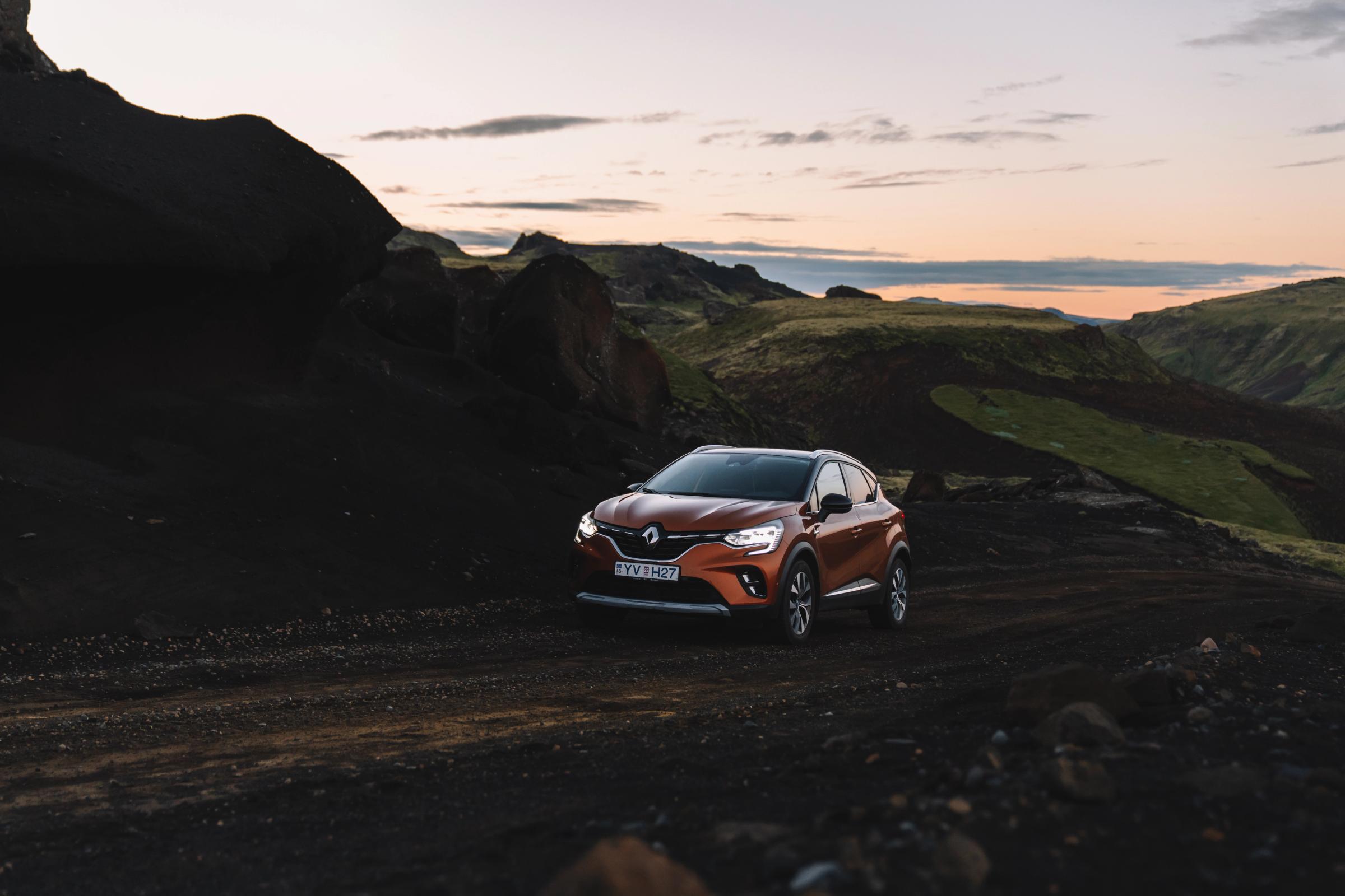 Renault Captur parked on a gravel road through dark lava rock terrain at dusk