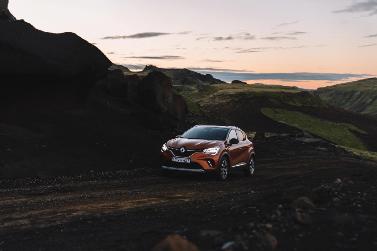 Renault Captur parked on a gravel road through dark lava rock terrain at dusk