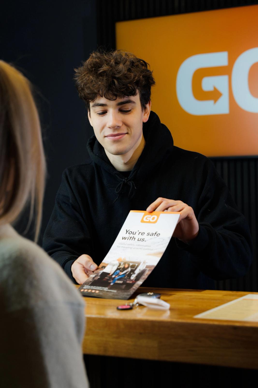 a man is holding a pamphlet that says " you 're safe with us "