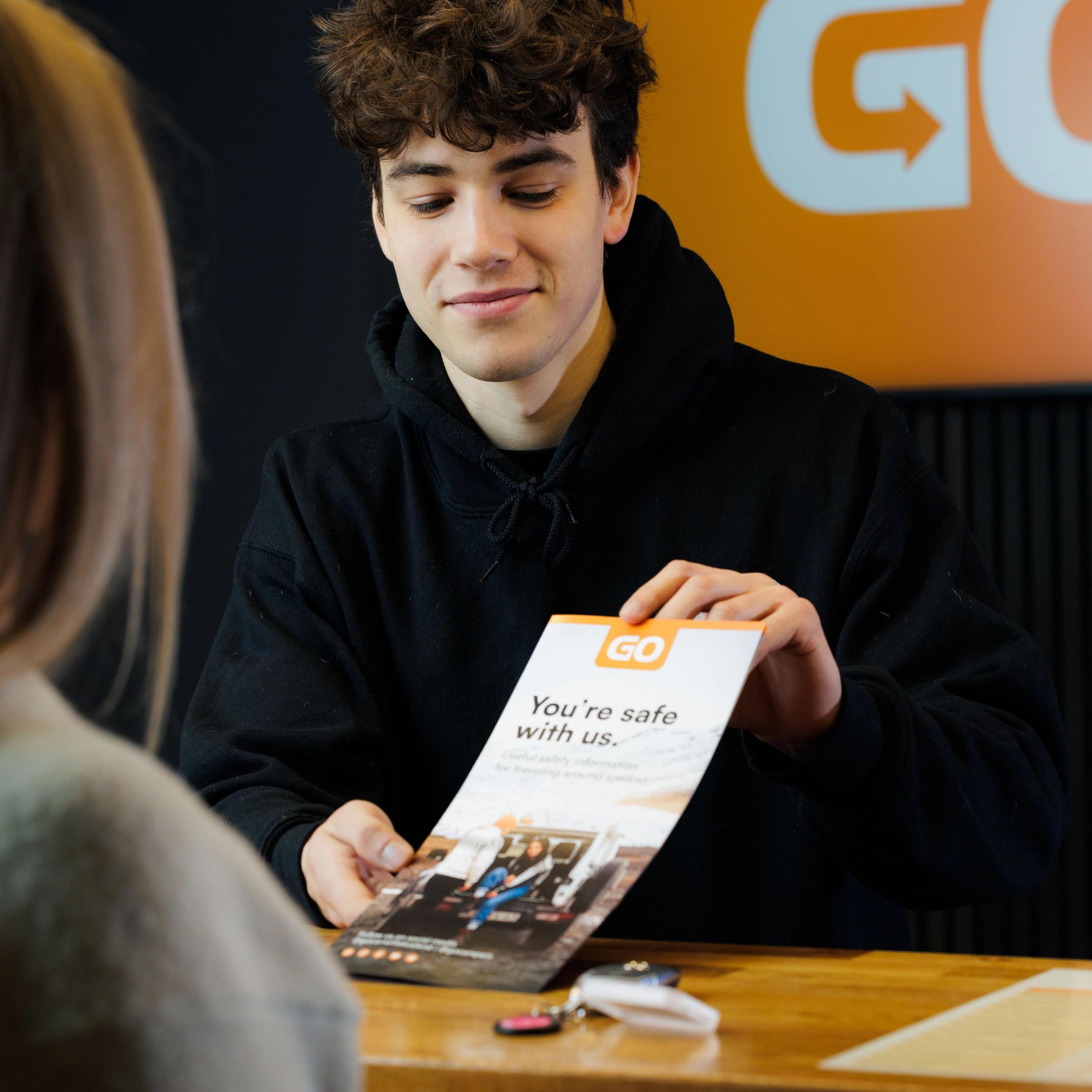 a man is holding a pamphlet that says " you 're safe with us "