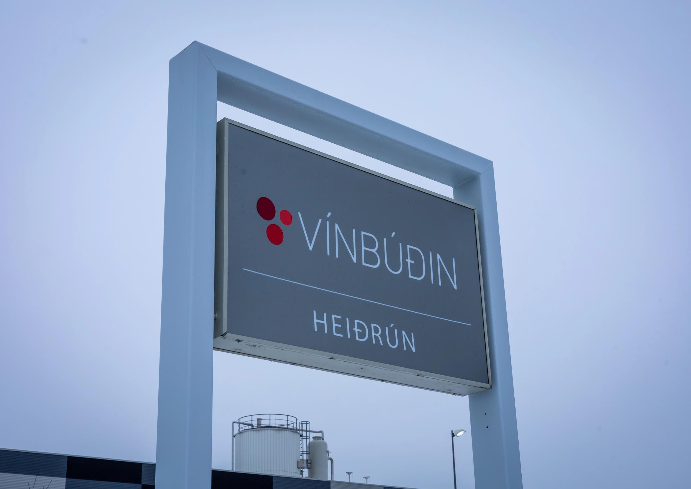 A grey sign displaying 'VÍNBÚÐIN HEIÐRÚN' with a red circular logo.