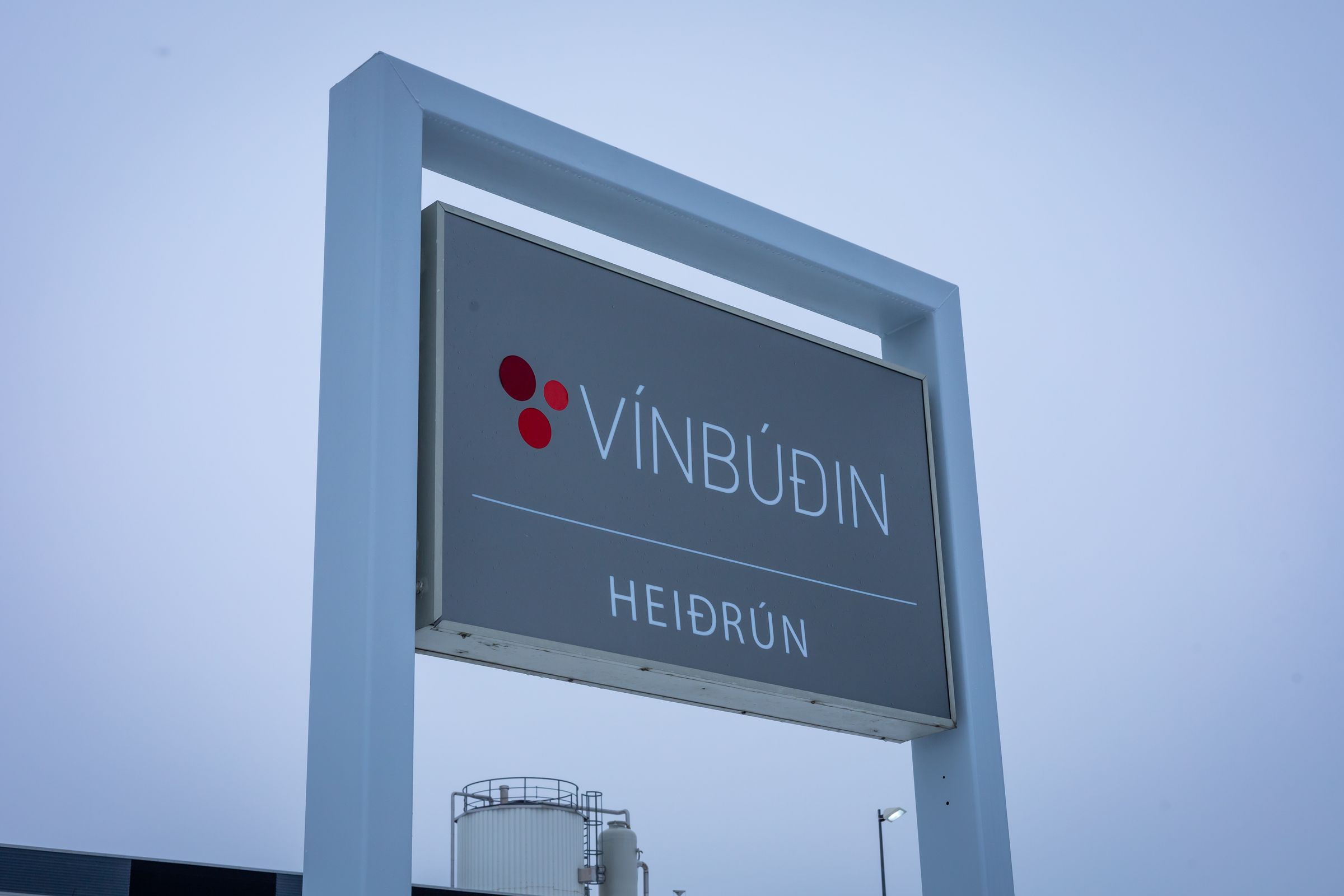 A grey sign displaying 'VÍNBÚÐIN HEIÐRÚN' with a red circular logo.