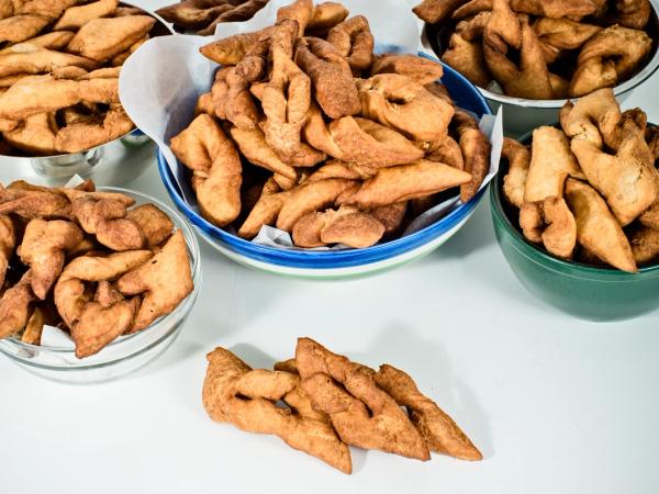 Bowls of golden-brown twisted fried pastries on a white surface.