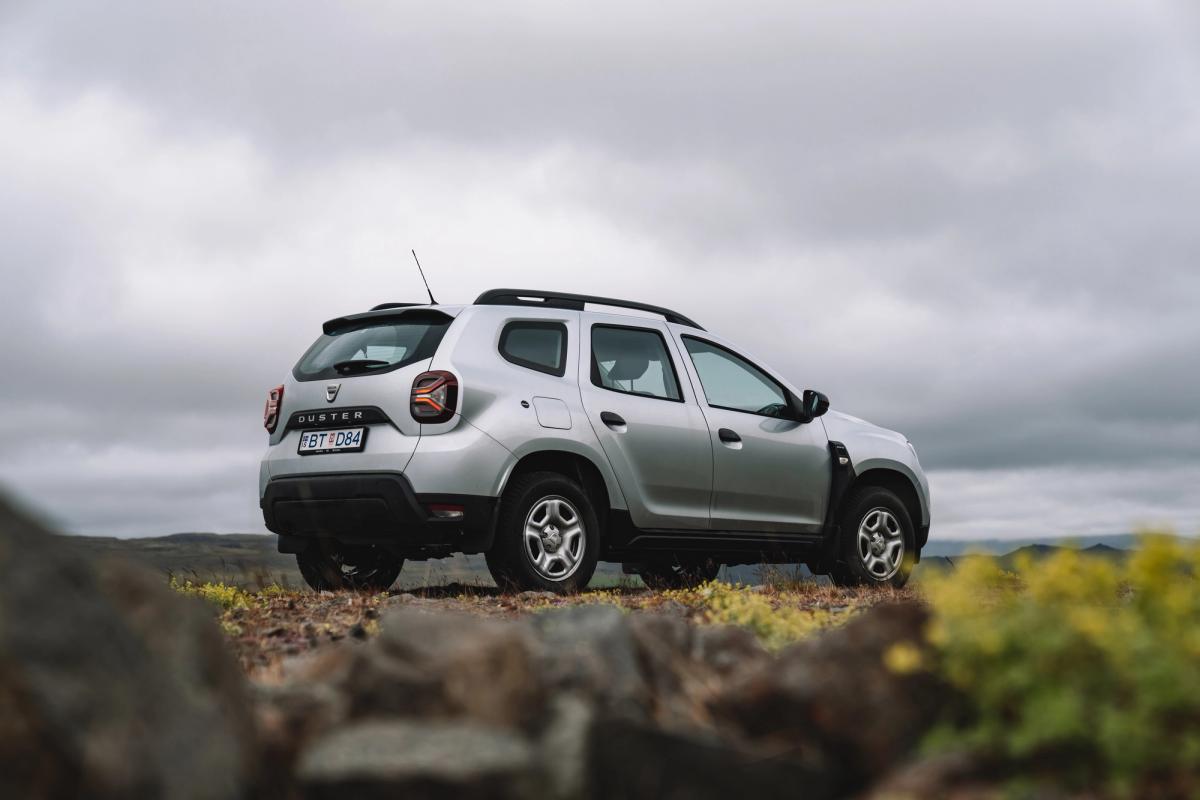 Dacia Duster rear quarter view parked on rocky ground with open landscape and cloudy sky