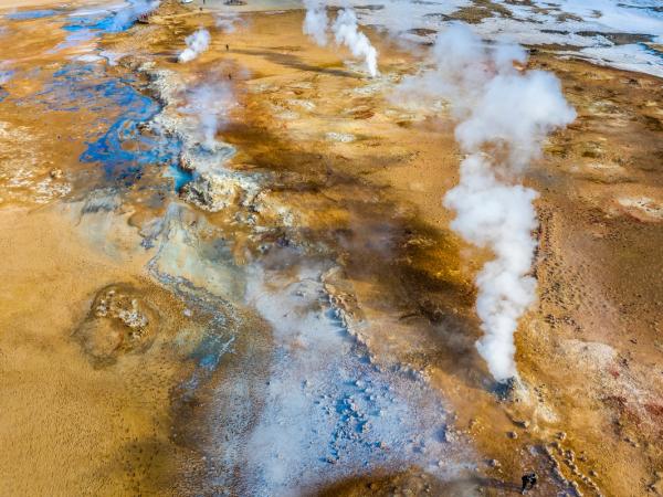 Aerial view of a colorful geothermal landscape with steaming vents.