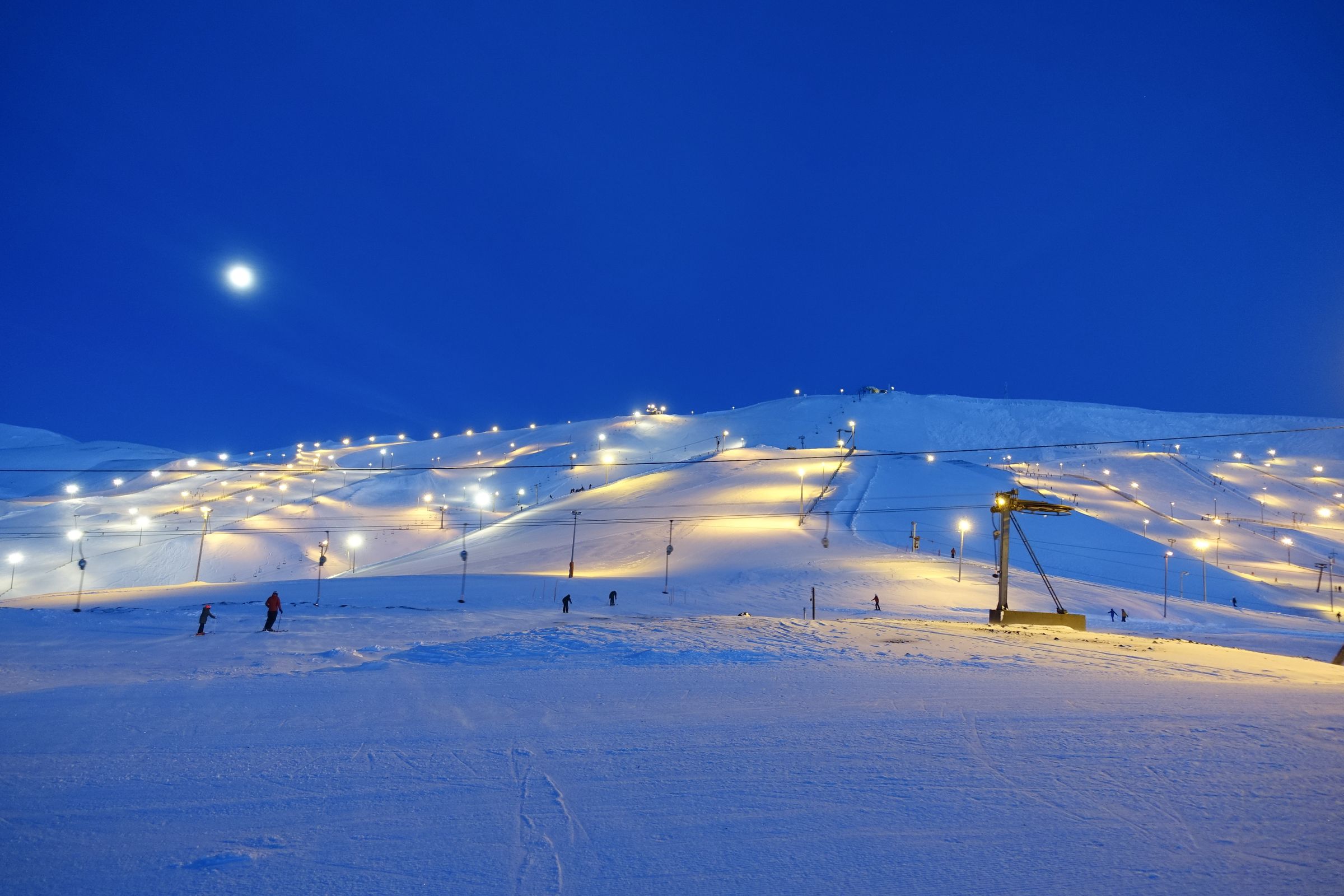 people skiing down a snow covered slope at night
