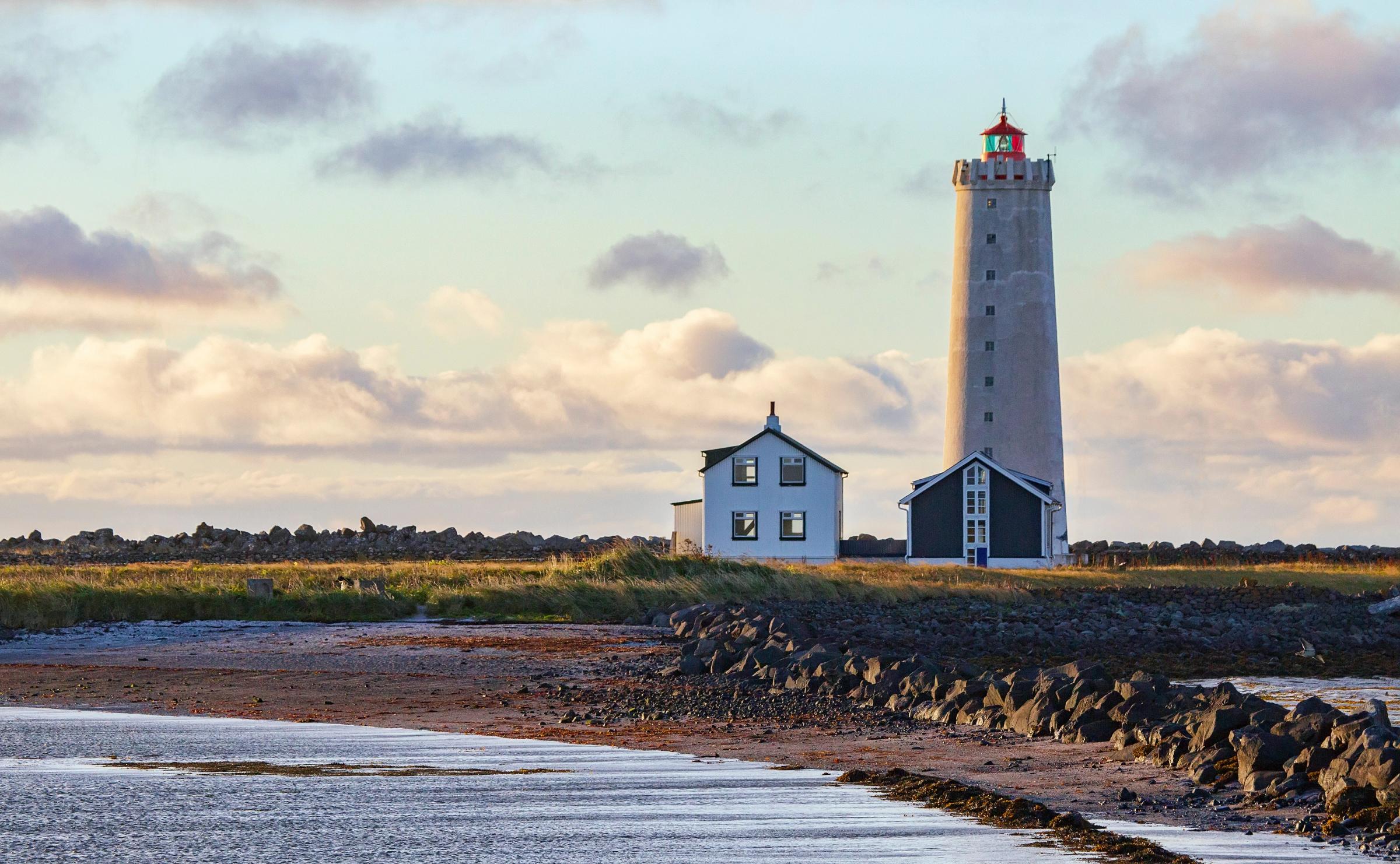 a white lighthouse with a house next to it an small beach
