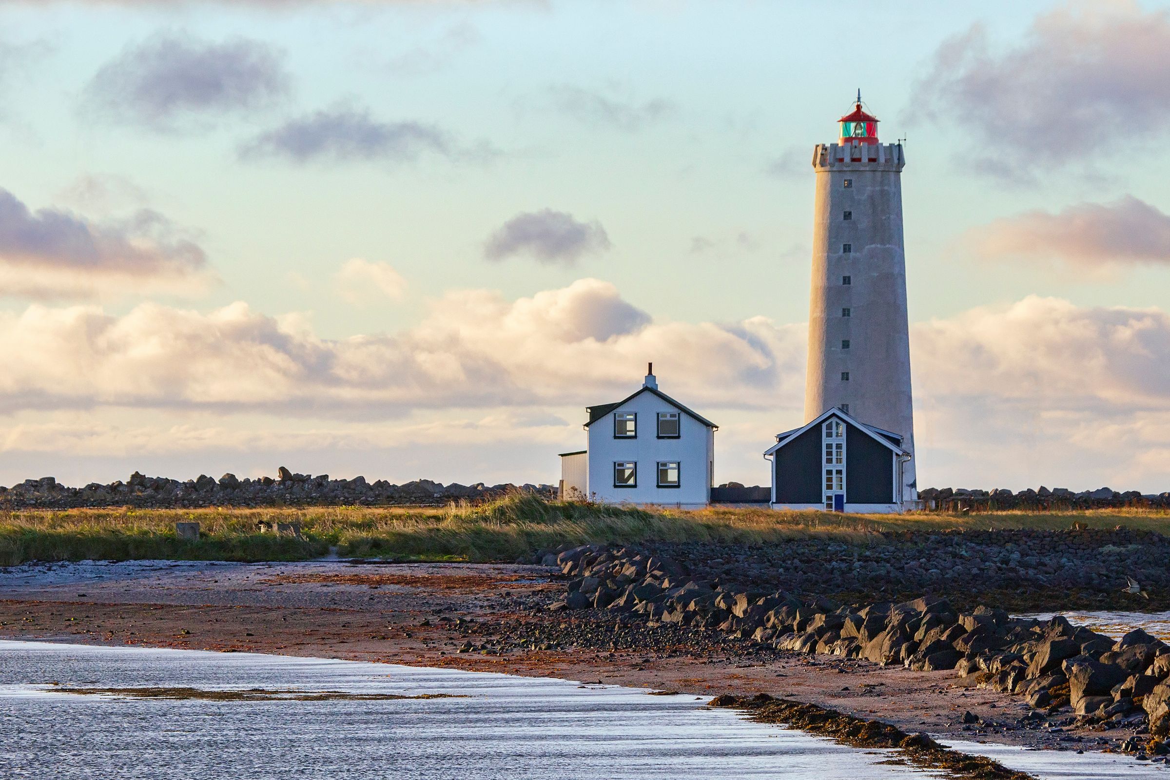 a white lighthouse with a house next to it an small beach